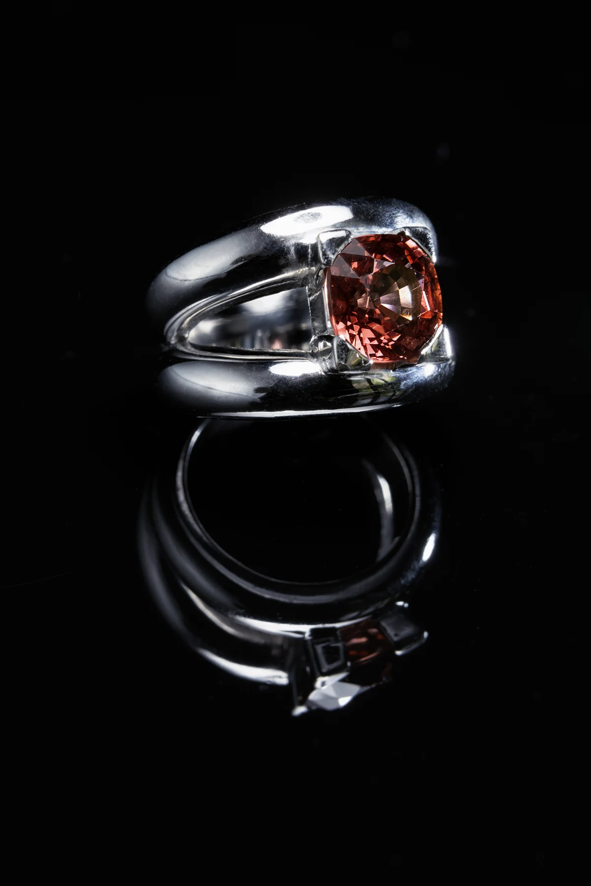 Bague Spinelle à pierre rouge et monture claire, photographiée sur fond noir