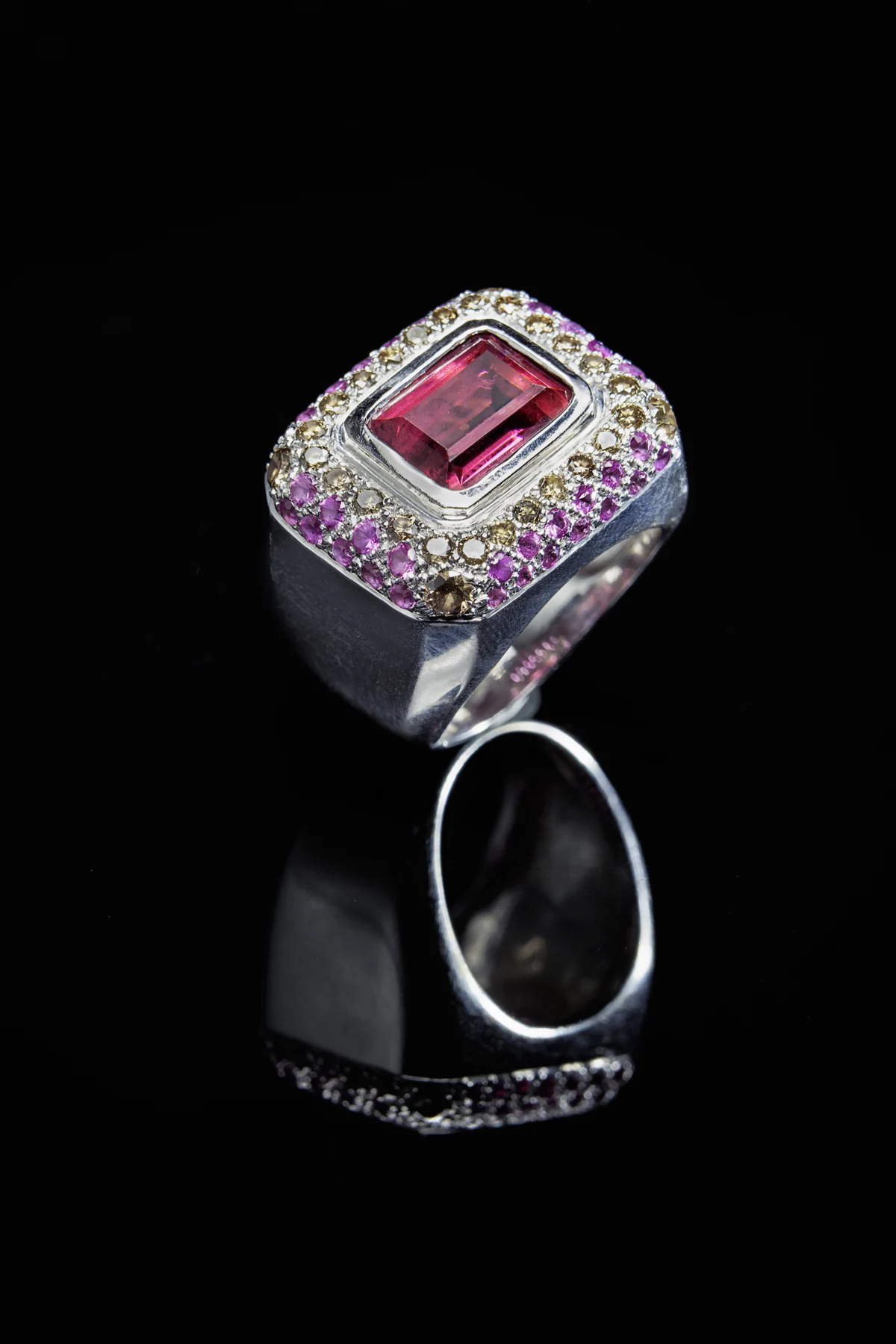 Bague Spinelle à pierre centrale rose rectangulaire et entourage de petites pierres, sur fond noir