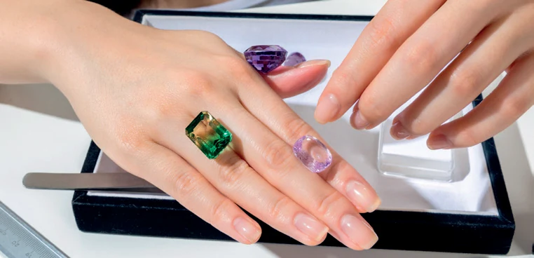 Sélection de pierres violettes et vertes présentées sur des mains lors d’un choix de gemmes chez Spinelle