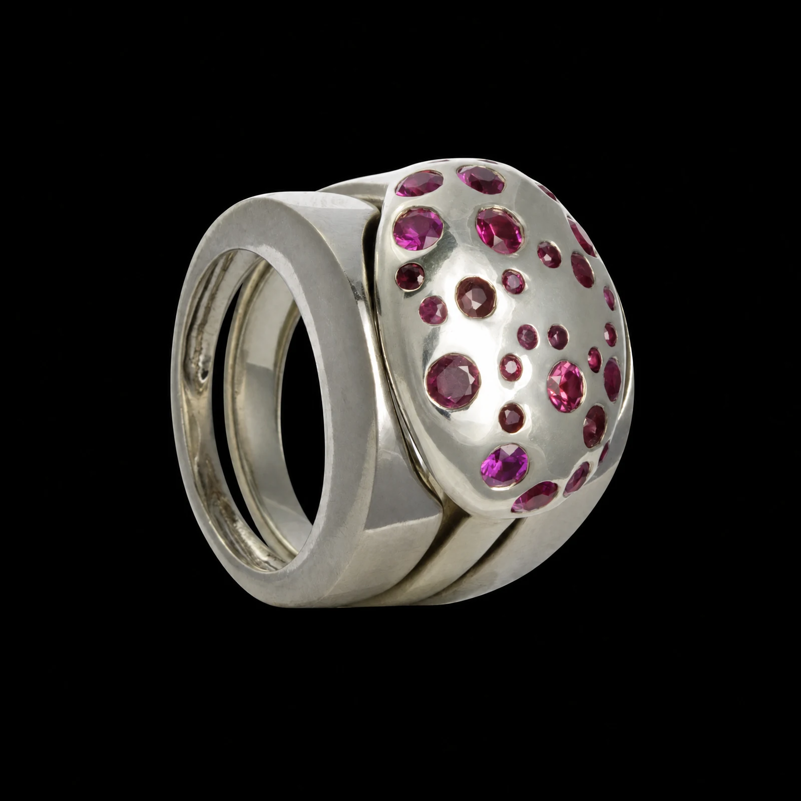 Bague large de la collection Spin à monture claire et pierres roses réparties sur le dessus